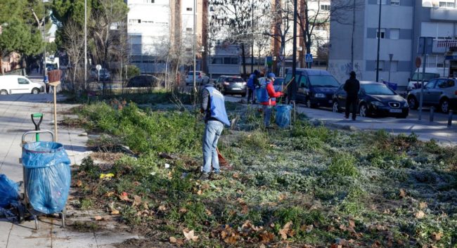 Operarios limpiando la basura acumulada durante semanas en la calle Godella de Villaverde, minutos antes de la convocatoria de Rita Maestre.